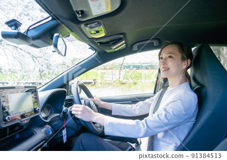 一個穿著夾克的年輕女子在明亮的白天開車 91384513