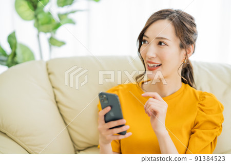 A young woman enjoying online shopping on her smartphone 91384523