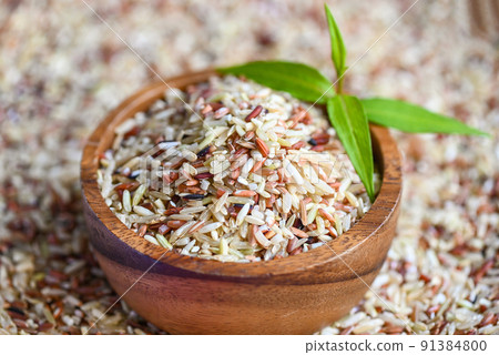 brown rice on wooden bowl and green leaf, raw various rice color mixed thai rice for cooking food , Loonzain rice brown black red white purple health food. 91384800