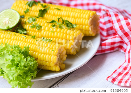 sweet corn food with salad vegetable lime coriander and lettuce, sweet corn cooked on white plate background, ripe corn cobs steamed or boiled sweetcorn for food vegan dinner or snack sweet corn food with salad vegetable lime coriander and lettuce, sweet corn cooked on white plate background, ripe corn cobs steamed or boiled sweetcorn for food vegan dinner or snack 91384905