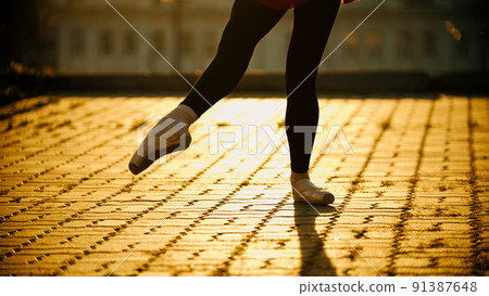 Feet of young woman ballerina dancing on the roof in the pointe shoes - yellow sunset 91387648
