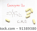 Chemical formula of Coenzyme Q10 and some pills on the paper background. Useful vitamin quinone for cells. Close-up. 91389380