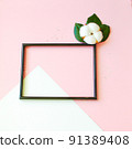 Summer modern composition. Black photo frame, green leaves and flower cotton of tree on pastel pink background. Flat lay, top view, copy space 91389408