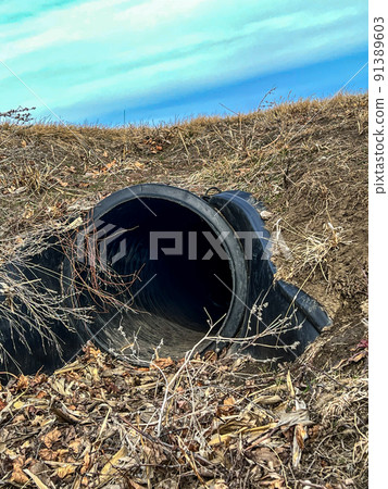 HDPE drainage culvert under a road entrance. Pipe is used to convey stormwater between ditches. 91389603