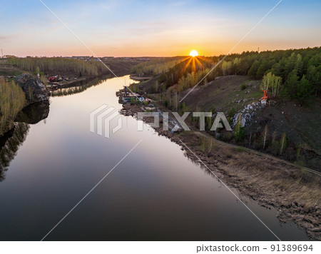 Beauriful sunset view along the Iset river and rocks near Kamensk-Uralskiy. A scenic sunset at the river. Kamensk-Uralskiy, Sverdlovsk region, Ural mountains, Russia. Aerial view 91389694