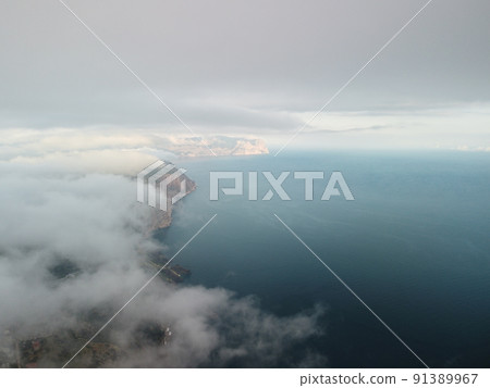 Aerial view. Blue sky sun and fog over calm sea. The drone flies over foggy and fluffy clouds. Abstract aerial nature summer ocean sunset sea and sky background. Vacation, travel and holiday concept. 91389967