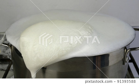 Cows milk boiled and overflowing. Boiling milk escapes from saucepan. Forgot milk on stove. Selective focus. 91393588