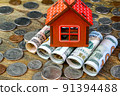 House on top of american dollars banknotes rolled into tube and many us coins. Home cash and saving of financial assets for investment of real estate and property. 91394488