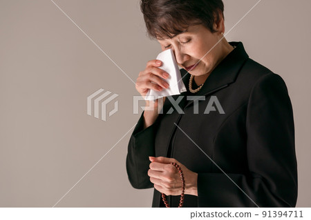 A woman wiping her tears with a handkerchief 91394711