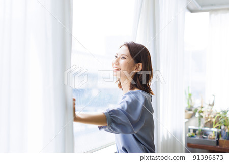 Woman opening curtain 91396873