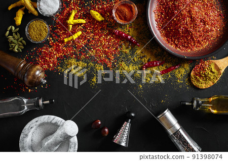 Cooking using fresh ground spices with mortar and small bowls of spice on a black table with powder spillage on its surface, overhead view with copyspace Cooking using fresh ground spices with mortar and small bowls of spice on a black table with powder spillage on its surface, overhead view with copyspace 91398074