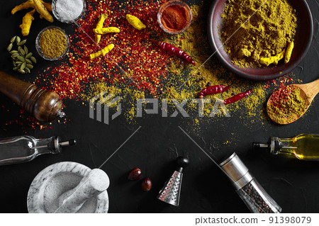 Cooking using fresh ground spices with mortar and small bowls of spice on a black table with powder spillage on its surface, overhead view with copyspace Cooking using fresh ground spices with mortar and small bowls of spice on a black table with powder spillage on its surface, overhead view with copyspace 91398079