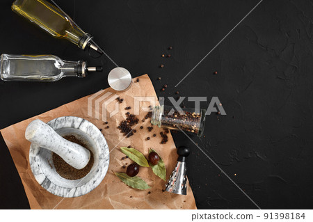 White mortar and pestle with dried peppers in flat lay on black background 91398184