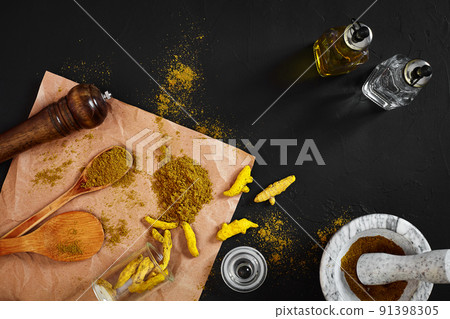 Turmeric Haldi powder in small bowl with raw whole in marble mortar over black background with copy space Turmeric Haldi powder in small bowl with raw whole in marble mortar over black background with copy space 91398305