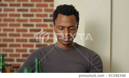 African american man browsing internet on mobile phone, holding beer bottle to relax. Young adult enjoying drink and looking at social media website on smartphone. Handheld shot. Close up. African american man browsing internet on mobile phone, holding beer bottle to relax. Young adult enjoying drink and looking at social media website on smartphone. Handheld shot. Close up. 91398306
