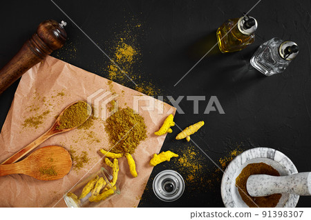 Turmeric Haldi powder in small bowl with raw whole in marble mortar over black background with copy space Turmeric Haldi powder in small bowl with raw whole in marble mortar over black background with copy space 91398307