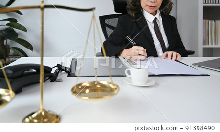 Cropped shot of middle aged female lawyer working and notary signs the documents at personal office. Lawyer, justice and law and attorney concept Cropped shot of middle aged female lawyer working and notary signs the documents at personal office. Lawyer, justice and law and attorney concept 91398490
