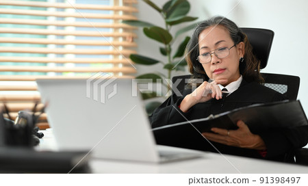Focused mature female lawyer in judge uniform working with documents at office. consultant lawyer, justice and law ,attorney, court judge, concept Focused mature female lawyer in judge uniform working with documents at office. consultant lawyer, justice and law ,attorney, court judge, concept 91398497