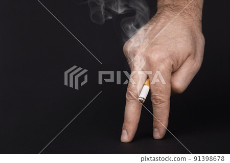 Cigarette in fingers of concept of causing Cigarette in fingers of concept of causing 91398678