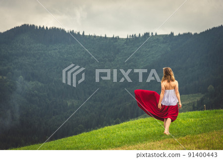 Woman in red at the green fields of Mountains Woman in red at the green fields of Mountains 91400443