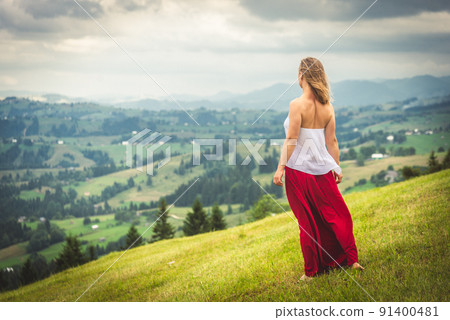 Woman in red at the green fields of Mountains 91400481
