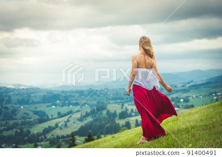 Woman in red at the green fields of Mountains 91400491