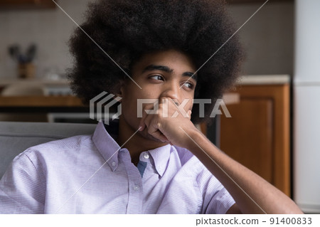 Pensive African teenage guy deep in thoughts sit on sofa 91400833