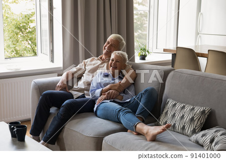 Joyful older couple relax on sofa laughing watching comedy movie Joyful older couple relax on sofa laughing watching comedy movie 91401000