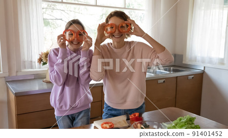 Funny portrait smiling mother and teenage daughter holding red pepper 91401452