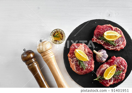 Fresh raw beef steaks with herbs, garlic, olive oil, pepper, salt and rosemary on black board: Tenderloin, Striploin, Rib Eye Fresh raw beef steaks with herbs, garlic, olive oil, pepper, salt and rosemary on black board: Tenderloin, Striploin, Rib Eye 91401951