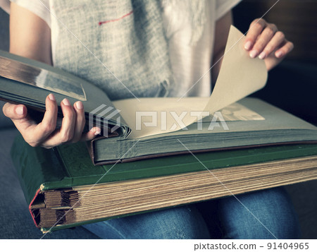 Young woman is looking through family photo album to engage in a memory. Happy memories from the old days Young woman is looking through family photo album to engage in a memory. Happy memories from the old days 91404965
