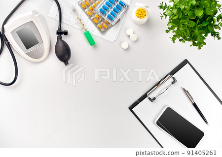 Top view of doctor's desk table, blank paper on clipboard with pen, electronic manometer to measure the blood pressure. 91405261