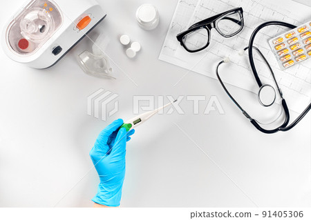 Doctor measuring temperature and holding a digital thermometer, desktop with medical equipment on white background, top view Doctor measuring temperature and holding a digital thermometer, desktop with medical equipment on white background, top view 91405306