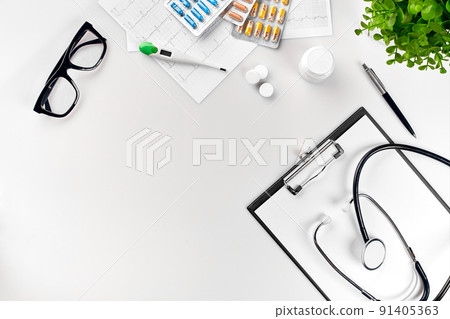 Doctor's office desk with medical documents, charts, eyeglasses and stethoscope. Top view. Copy space 91405363