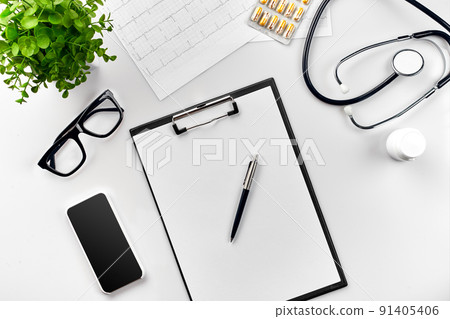 Stethoscope in the office of doctors.Top view of doctor's desk table, blank paper on clipboard with pen. Copy space. Designer's blank 91405406