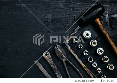 Copy space of working tools on a black wooden surface. Nippers, wrench keys, pliers, screwdriver, hammer. Top view. 91405950