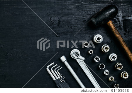 Renovating a car. A set of repair tools- hex keys, a hammer and a screwdriver on a black wooden background. Close up. Top view. 91405958