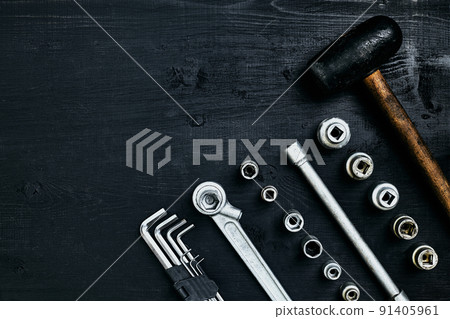 Renovating a car. A set of repair tools- hex keys, a hammer and a screwdriver on a black wooden background. Close up. Top view. 91405961