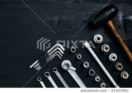 Renovating a car. A set of repair tools- hex keys, a hammer and a screwdriver on a black wooden background. Close up. Top view. 91405962