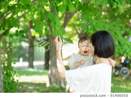Mother and 1 year old girl touching fresh green leaves Mother and 1 year old girl touching fresh green leaves 91406058