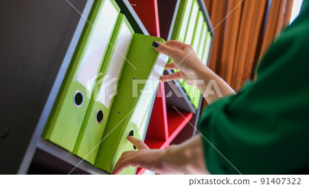 Secretary takes out business folder with documents from cabinet 91407322