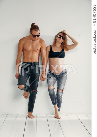 Joyful family. Portrait of isolated cute recently married people pregnant waiting for baby wearing in denim and sunglasses over white background 91407655