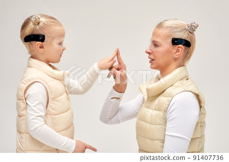 Woman with little girl in futuristic costume wearing smart led glasses of virtual reality while touching air. Augmented reality game, future technology, AI concept. VR. Woman with little girl in futuristic costume wearing smart led glasses of virtual reality while touching air. Augmented reality game, future technology, AI concept. VR. 91407736