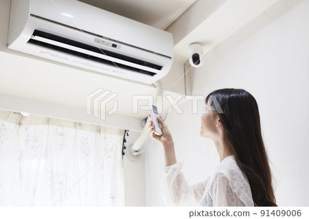 Woman turning on the air conditioner 91409006