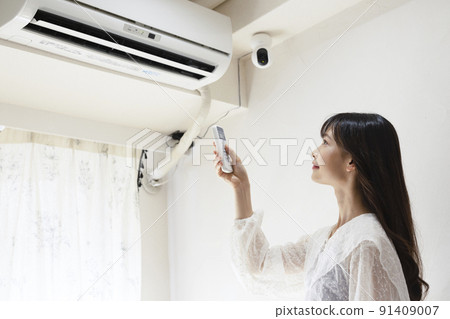 Woman turning on the air conditioner 91409007