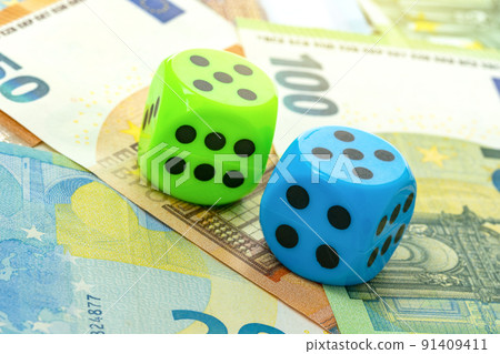 Blue and green dice close-up on a background of euro banknotes 91409411