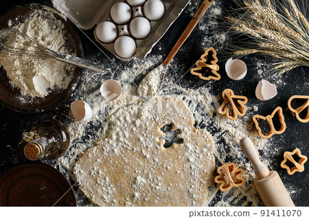 Dough for ginger biscuits rolled up on a table and cut using molds 91411070