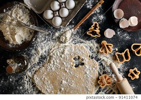 Dough for ginger biscuits rolled up on a table and cut using molds Dough for ginger biscuits rolled up on a table and cut using molds 91411074