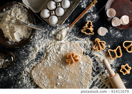 Dough for ginger biscuits rolled up on a table and cut using molds Dough for ginger biscuits rolled up on a table and cut using molds 91411079