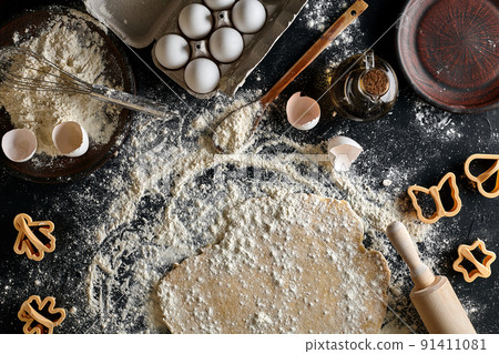 Cooking dough for cookies, butter, eggs, cooking equipment, flour on a black table. Top view with copy space, mockup for menu, recipe or culinary classes. Baking background. 91411081